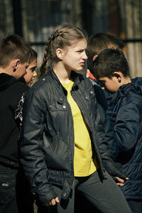 Teenage girl looking away while standing with friends