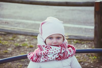 Portrait of cute girl in warm clothing against railing