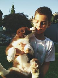 Smiling boy carrying puppy while standing in back yard