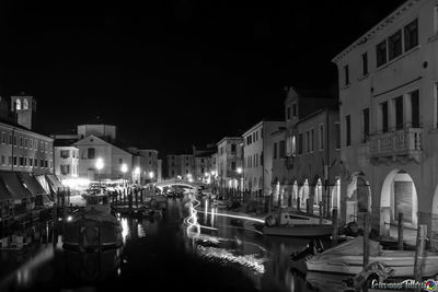 Boats moored on illuminated buildings in city at night