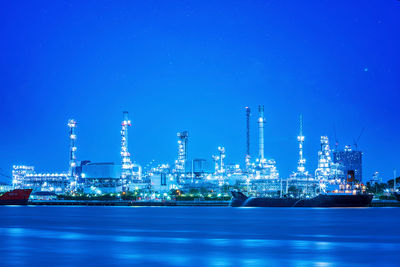 Illuminated factory against blue sky at night