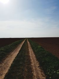 Road amidst field against sky