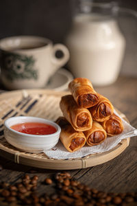 Fried spring rolls with a sweet chili sauce on a rattan plate . malaysian snacks. 