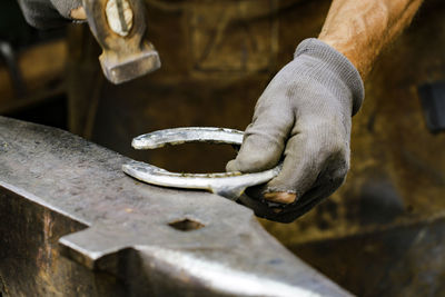 Cropped image of blacksmith hammering horseshoe on anvil