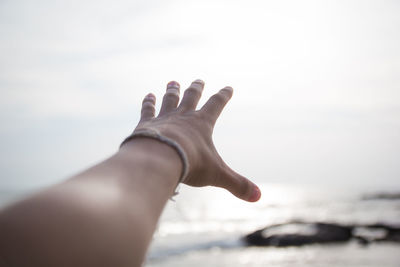 Low angle view of hand against sea against sky