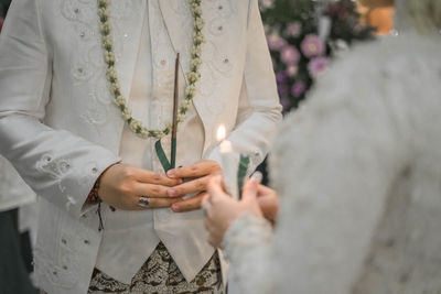 Midsection of bride and groom performing rituals during wedding ceremony