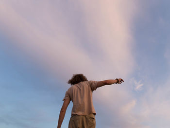 Rear view of woman standing against sky during sunset