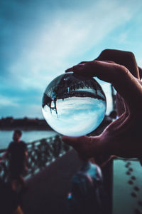 Close-up of hand holding glass against sky