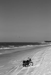 Man riding motorcycle on beach against sky