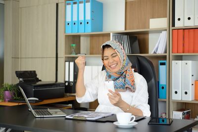 Woman using smart phone while sitting on table