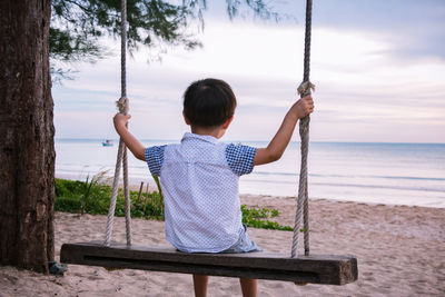 Rear view of boy sitting on swing