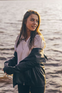 Smiling woman looking away while standing in sea