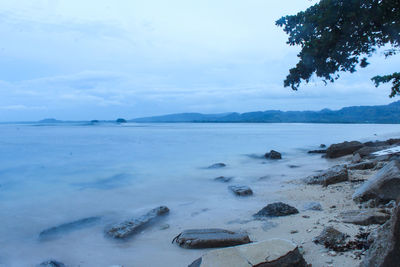 Scenic view of beach against mountains and cloudy sky