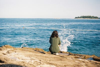 Rear view of woman looking at sea against clear sky