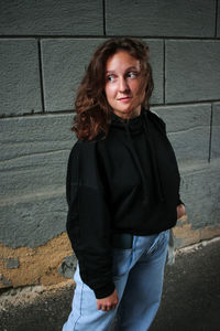 Portrait of teenage girl standing against wall