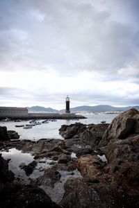 Lighthouse by sea against sky