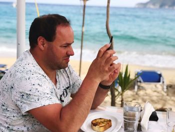 Midsection of man holding ice cream in sea