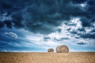 Hay bales on field against sky