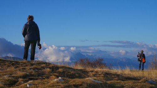 Rear view of man looking at mountains against sky