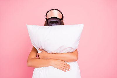 Midsection of woman holding umbrella against pink background