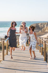 Full length of female friends on pier at beach