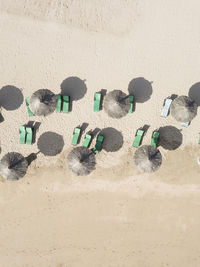 Aerial view of rows of beach umbrellas and empty deck chairs on sandy beach in summer