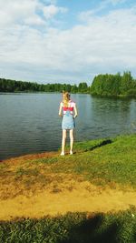 Woman standing by lake against sky