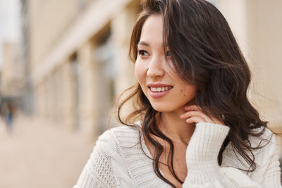 Portrait of young woman standing against wall