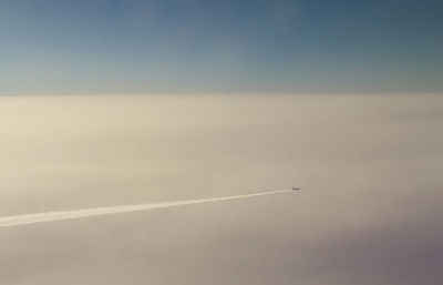 Aerial view of airplane flying against cloudy sky