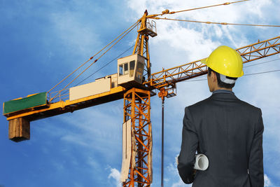 Low angle view of man standing at construction site against sky