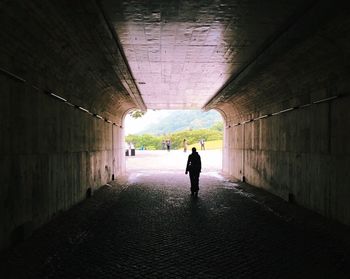 Rear view of man walking in tunnel