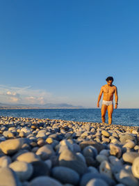 Front view of man standing at beach against sky