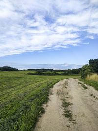 Scenic view of road amidst field against sky