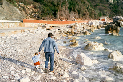 Rear view of men walking on rocks