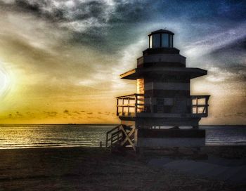 Lifeguard hut on beach against sky during sunset