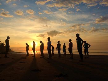 Silhouette people on beach against sky during sunset
