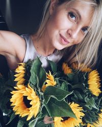 Portrait of woman with sunflowers traveling in car
