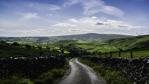 Road amidst agricultural landscape against sky