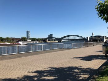 Bridge over river in city against clear blue sky