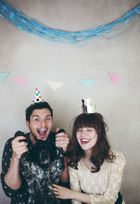 Cheerful couple with dog by wall during celebration