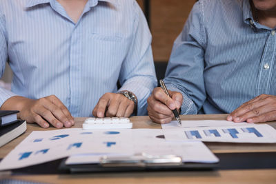 Midsection of businessmen working over graph in office