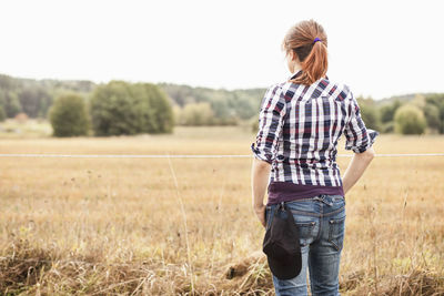 Rear view of female farmer standing at field