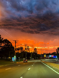 Cars on road against sky during sunset