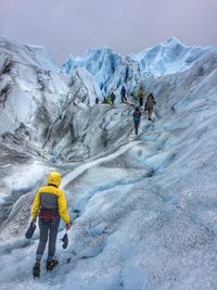 Rear view of people hiking on snowcapped mountains