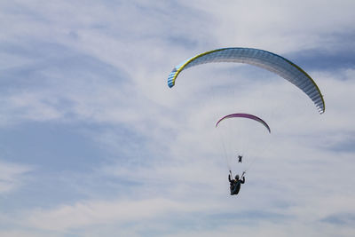 Low angle view of man paragliding against sky