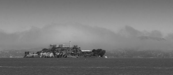 Trees on field by building against sky