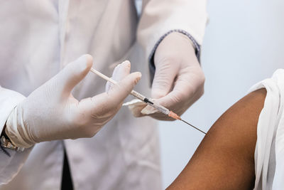 Close up of crop medic making injection for black female patient