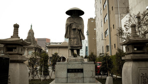 Statue amidst buildings against clear sky