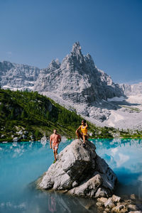 People on rock by mountain against sky