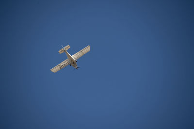 Low angle view of airplane against clear blue sky